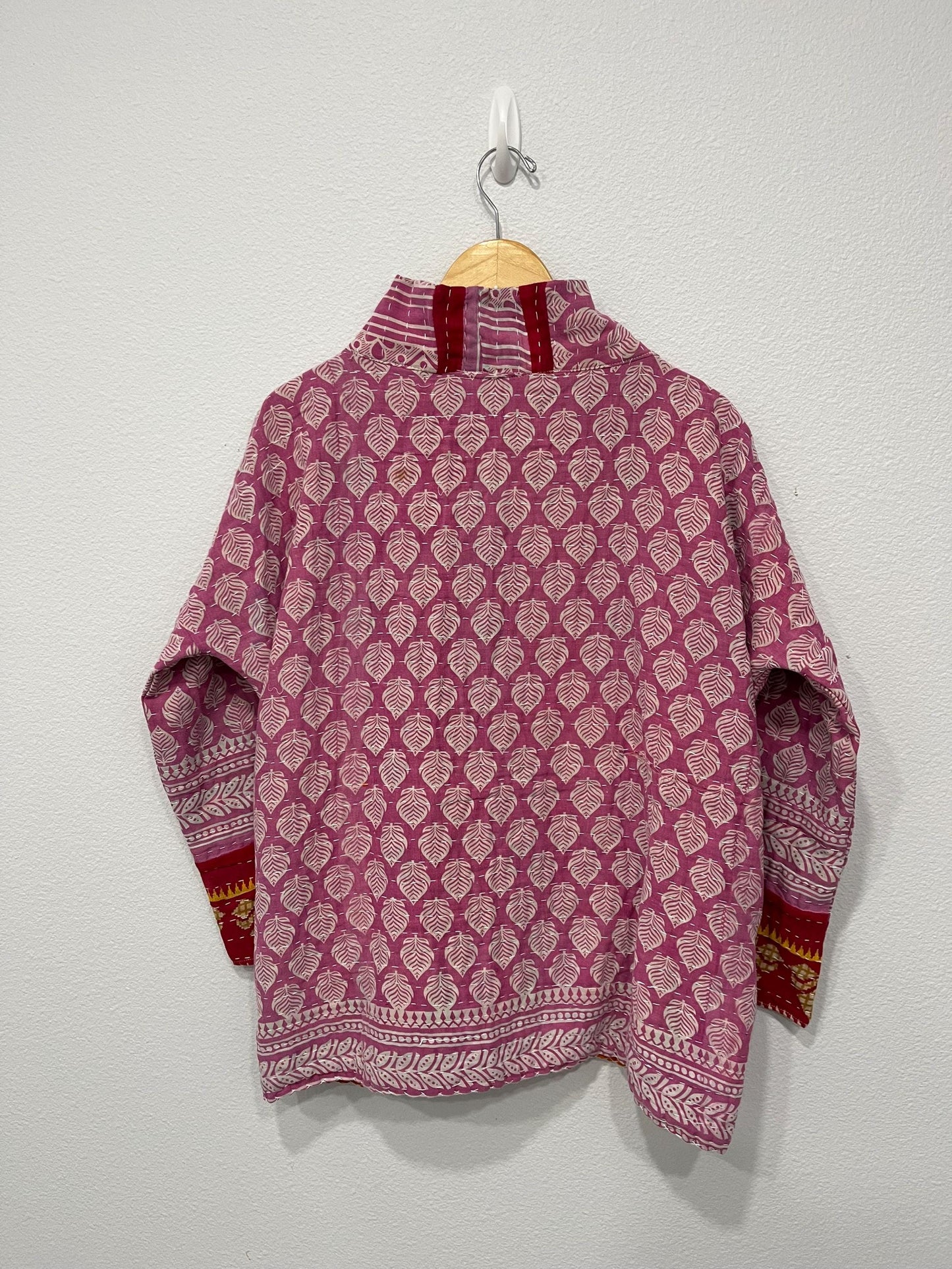 Unique, reversible quilted jacket. This Jacket is a lavender print fabric with red trim around the wrist. It is also soft and comfortable with pockets