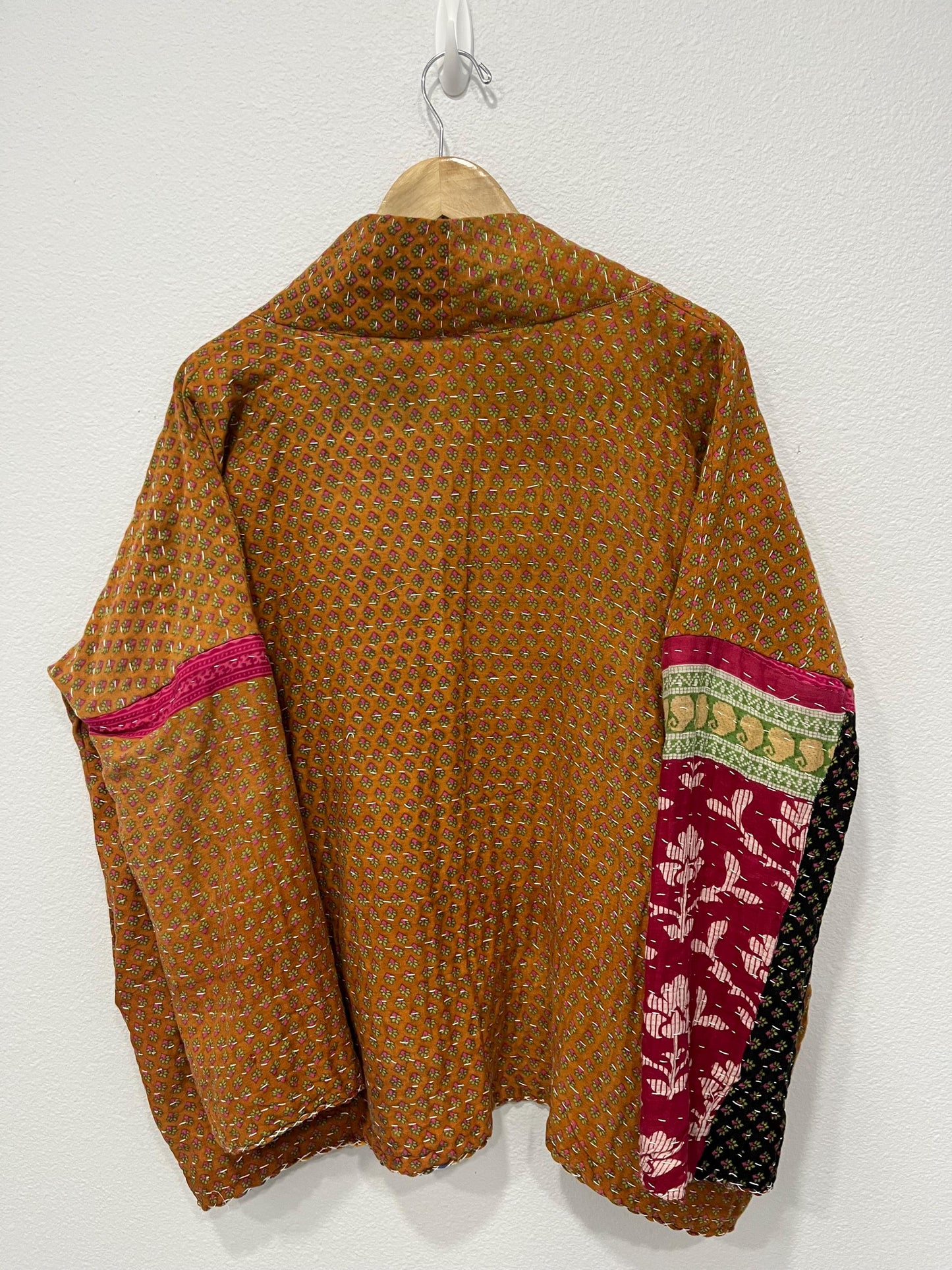 This one-of-a-kind quilted brown-gold small floral print and pink upper arm bands jacket is made of Kantha Cloth. It is wonderful for traveling as it is reversible for 2 looks in one and it is light weight for easy packing.