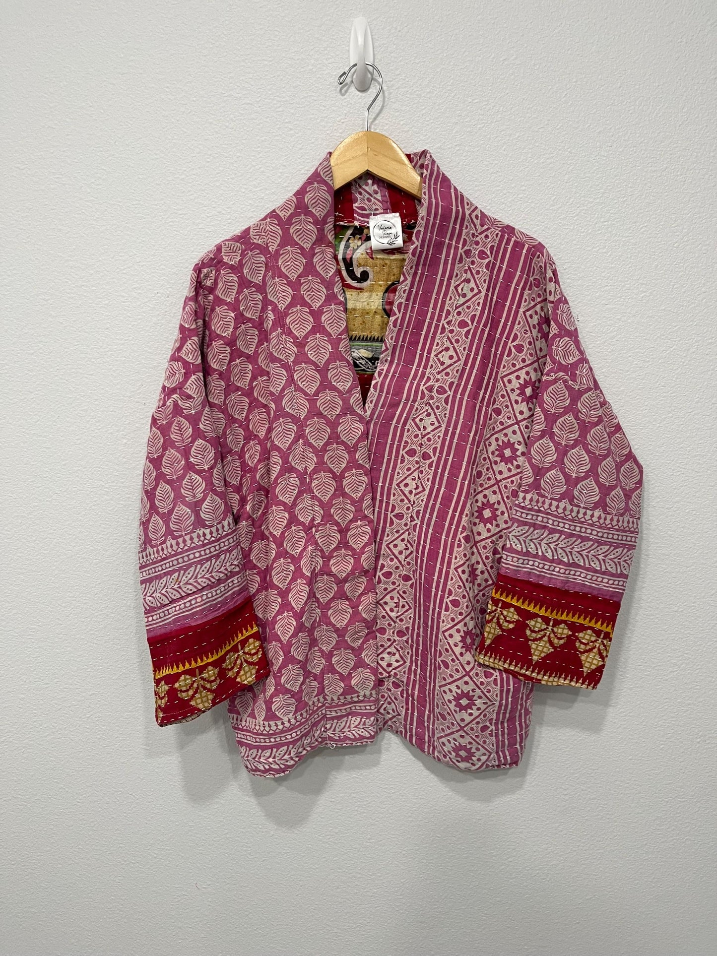Unique, reversible quilted jacket. This Jacket is a lavender print fabric with red trim around the wrist. It is also soft and comfortable with pockets