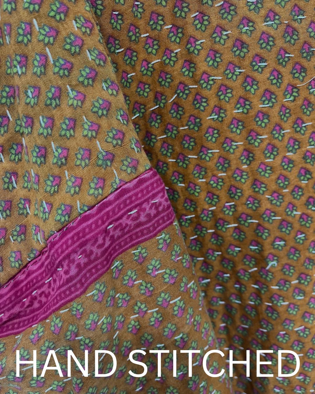 This one-of-a-kind quilted brown-gold small floral print and pink upper arm bands jacket is made of Kantha Cloth. It is wonderful for traveling as it is reversible for 2 looks in one and it is light weight for easy packing.