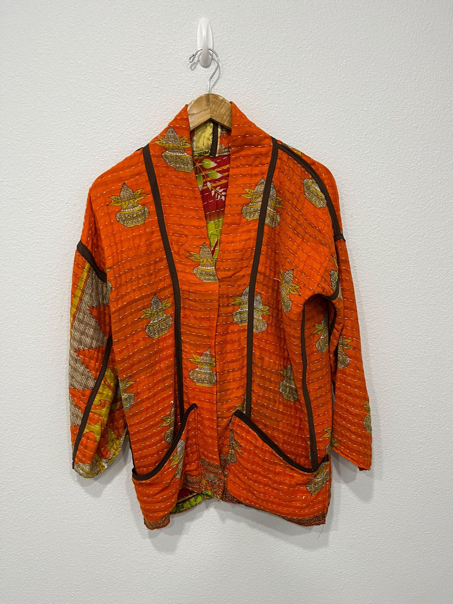 One-of-A-Kind quilted orange jacket with brown piping and pockets. Handmade with Kantha Cloth (procured through Fair Trade) and reversible