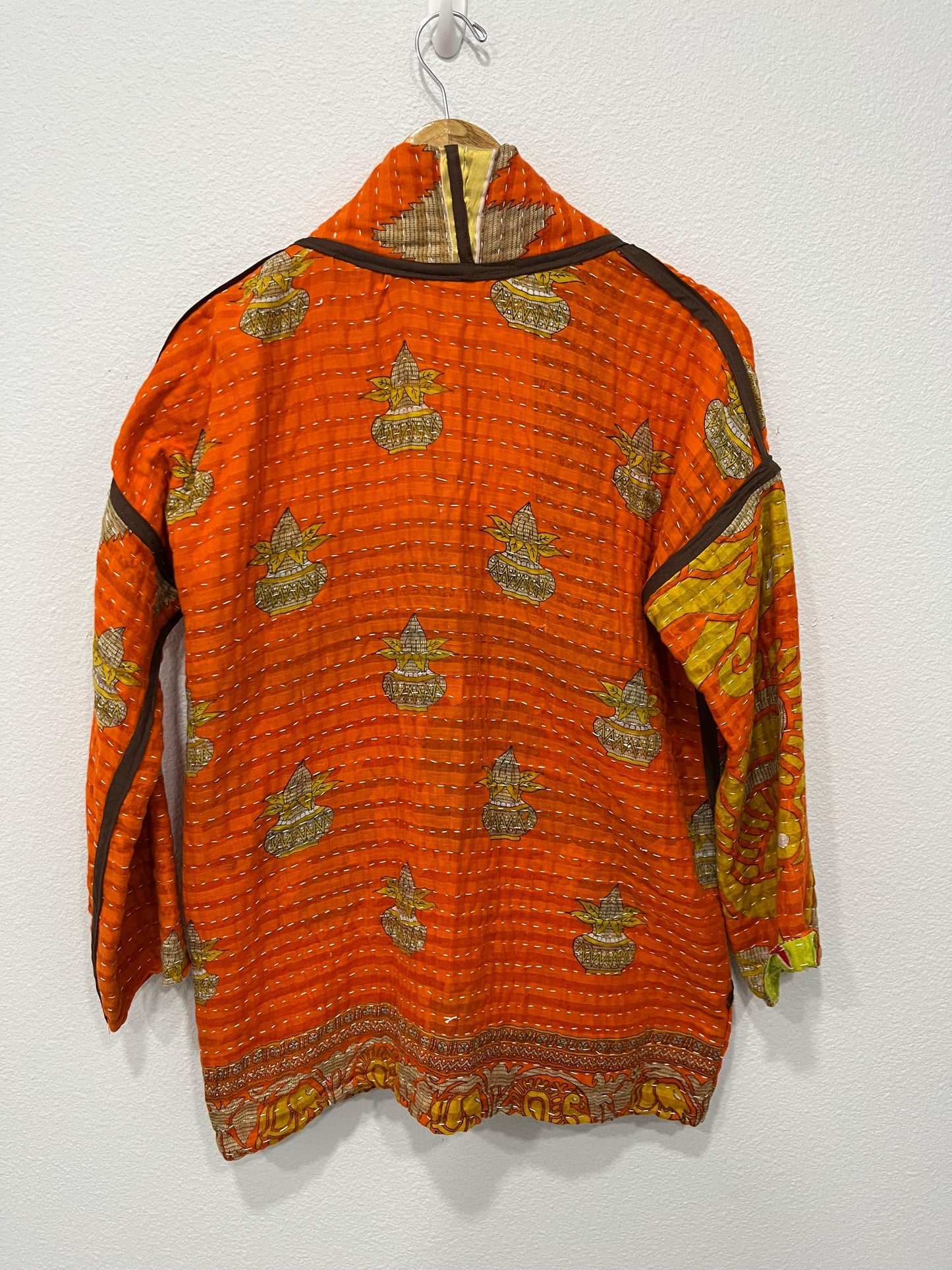 One-of-A-Kind quilted orange jacket with brown piping and pockets. Handmade with Kantha Cloth (procured through Fair Trade) and reversible