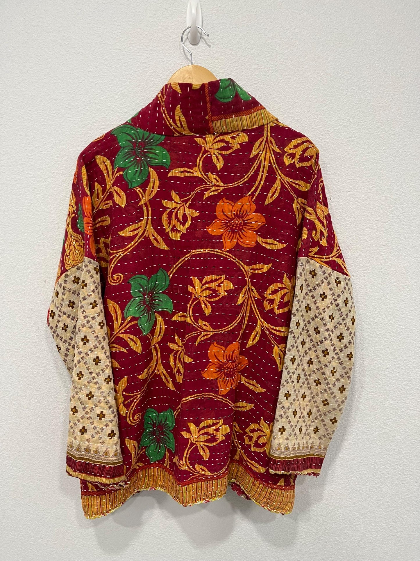 This One-of-a-kind Quilted Red, Green, and Gold jacket with Beige Sleeves is made from Kantha Cloth. It is great for traveling as it is reversible for 2 looks in one, and light weight for easy packing.